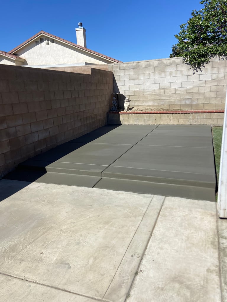 Empty garage driveway with concrete pads and cinder block walls under clear blue sky