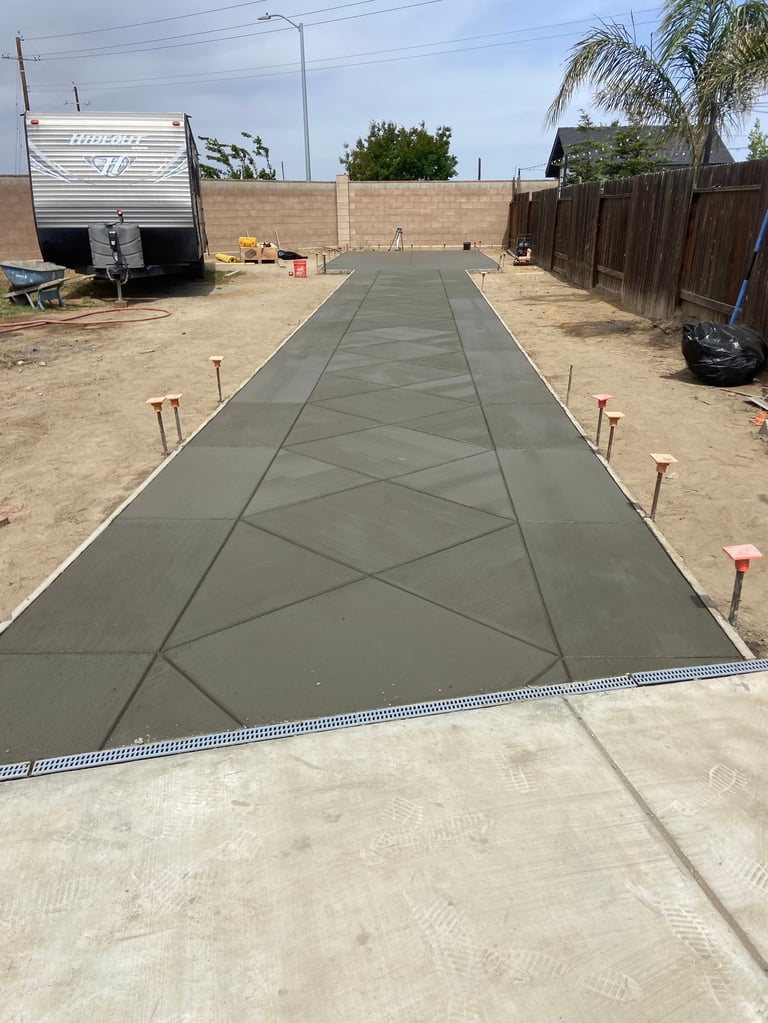 Freshly poured concrete driveway with geometric pattern in residential backyard construction site